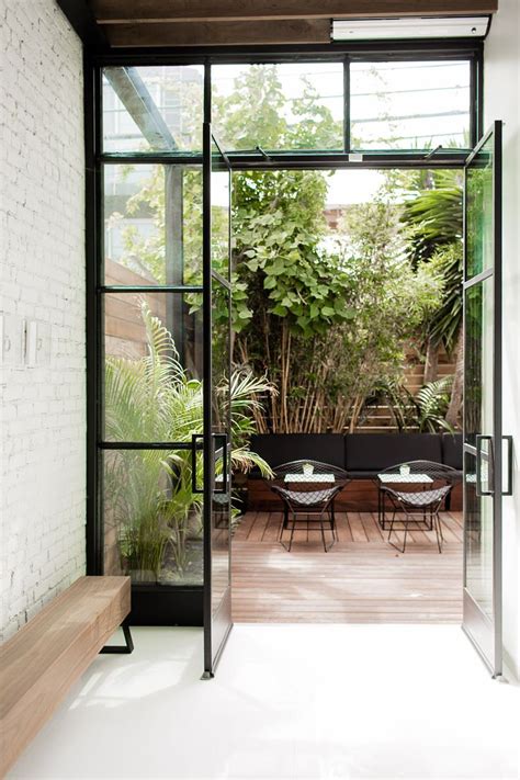 An Open Glass Door Leading To A Patio Area With Tables And Chairs On It