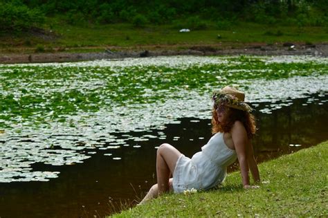 Premium Photo Side View Of Woman Sitting On Grass By Lake