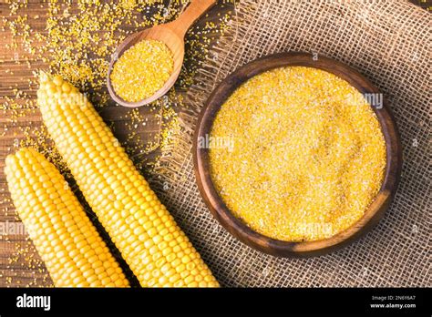 Corn Grits In A Wooden Bowl On The Background Of Fresh Corn On The Cob