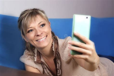 Fille Blonde Mignonne Sur Le Sofa Elle Regarde Son Smartphone Et Fait A Photo Stock Image Du