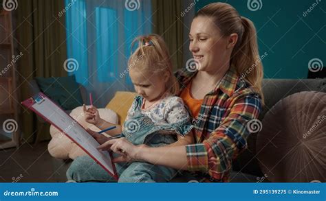 Happy Mom Helps Her Daughter Draw With Pencils While Sitting On The