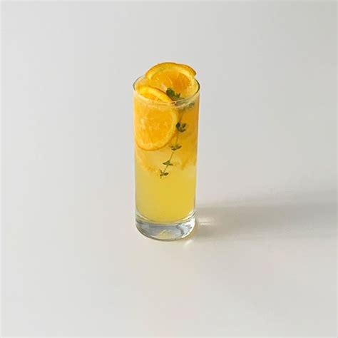 A Glass Filled With Orange Juice And Garnished With Mint