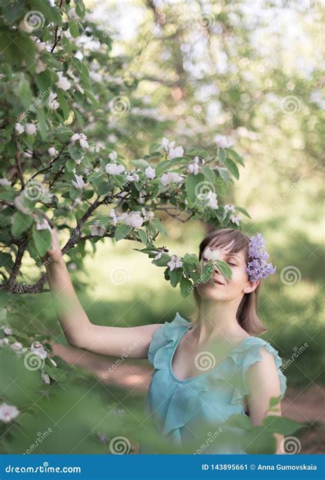 Young Happy Woman Walking In An Orchard In The Spring Flowers White