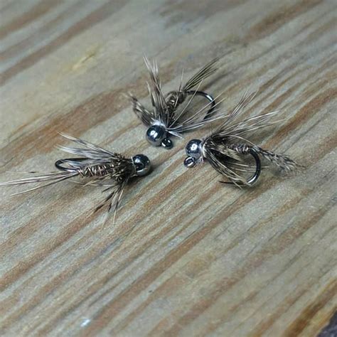 Three Flies Sitting On Top Of A Wooden Table