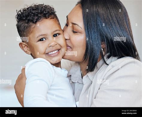 Mixed Race Woman Kissing Her Adorable Little Son On The Cheek While Bonding Together At Home