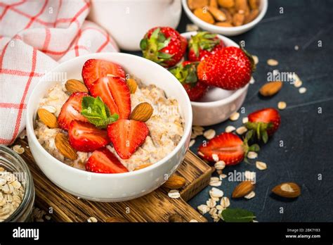 Oatmeal Porridge With Fresh Strawberry And Nuts On Dark Background