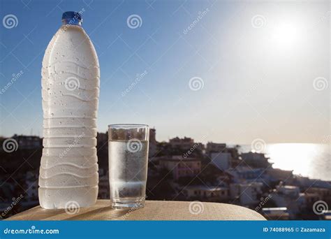 Water Bottle Full Of Water With Drops And Glass On The City And Sea