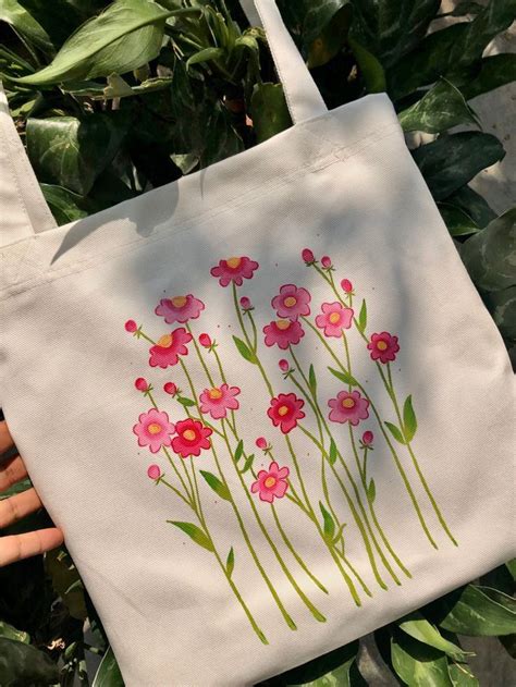 A White Bag With Pink Flowers Painted On The Side And Green Leaves In