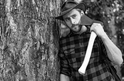 Premium Photo Lumberjack Worker Standing In The Forest With Axe