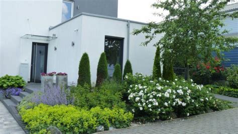 A White House Surrounded By Flowers And Trees