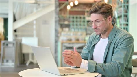 Pensive Middle Aged Man Thinking And Working On Laptop In Cafe Stock