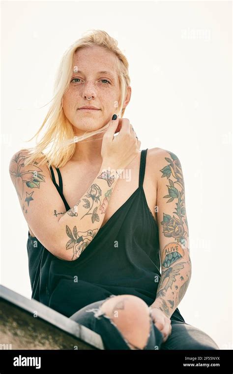 Blond Woman With Tattoo Sitting On Rooftop Stock Photo Alamy