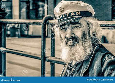 Old Man Sailor With A Thick Beard And A Captain`s Cap Observing Ships On The Quay Poland