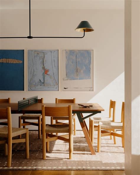 A Dining Room Table With Chairs And Paintings On The Wall