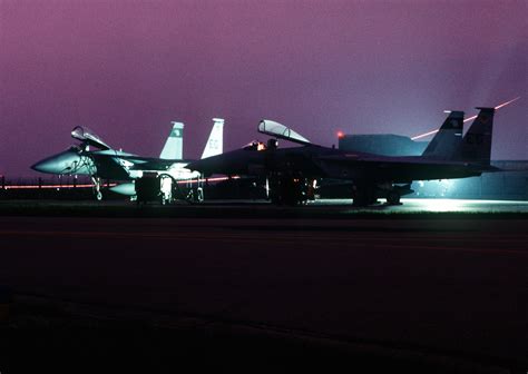 A left front view of two F-15 Eagle aircraft at night, as a post-flight ...