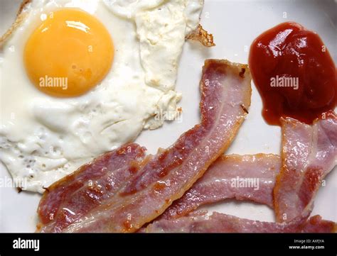 A Fried Egg And Two Rashers Of Streaky Bacon With Tomato Ketchup On A