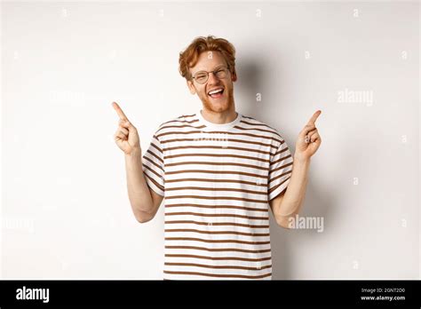 Happy Hipster Guy With Red Messy Hair And Glasses Smiling Pointing