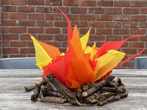 An Orange And Yellow Paper Flower Sitting On Top Of Sticks