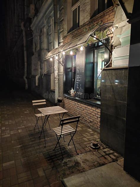 An Evening Cafe With A Table And Chairs Outside On The First Floor Of