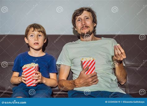 Father And Son Watching Tv And Eat Popcort In Evening At Home Stock