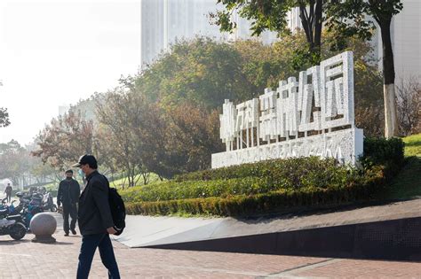 Two Men Walking Down The Sidewalk In Front Of A Building With A Sign On It