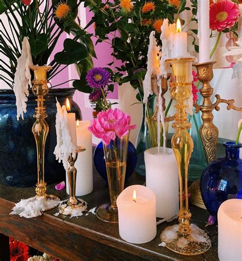 Many Candles Are Lit On A Mantle With Flowers In Vases And Other Decorative Items