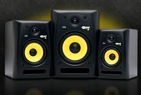 Three Black Speakers With Yellow Lights On The Sides And One Speaker In