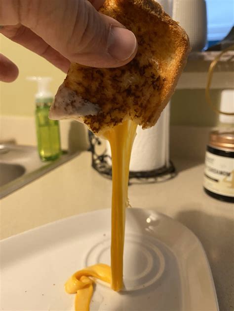 Melty drippy cheese from betwixt two pieces of bread grilled using mayo
