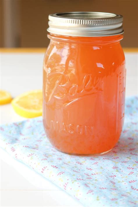 A Mason Jar Filled With Orange Juice Sitting On Top Of A Table Next To