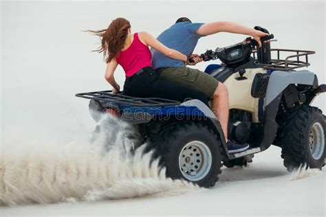 The Guy And The Girl Ride A Quad Bike In The Desert Having Fun And