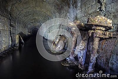 The Tunnel Of An Old Abandoned Mine With Rusty Remnants Of Trolleys