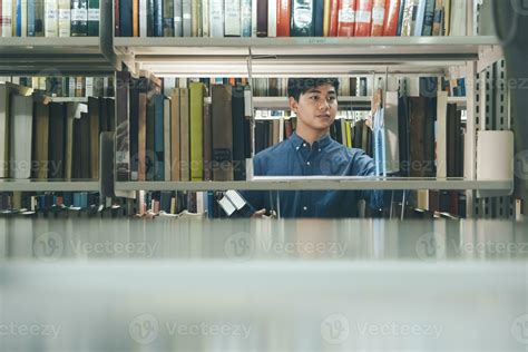 Young man choosing book at public library. 24770539 Stock Photo at Vecteezy