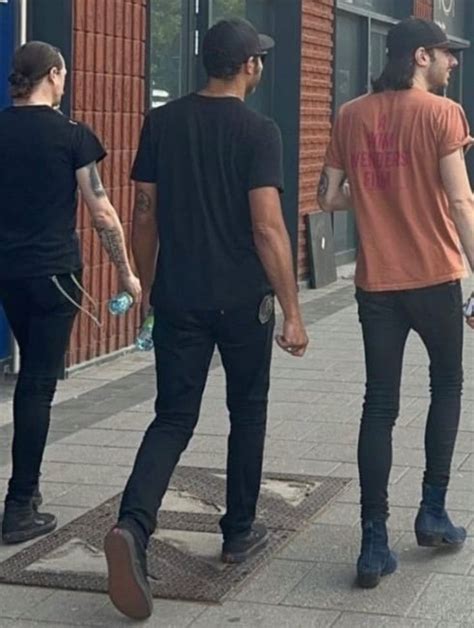 Three Men Are Walking Down The Sidewalk Together