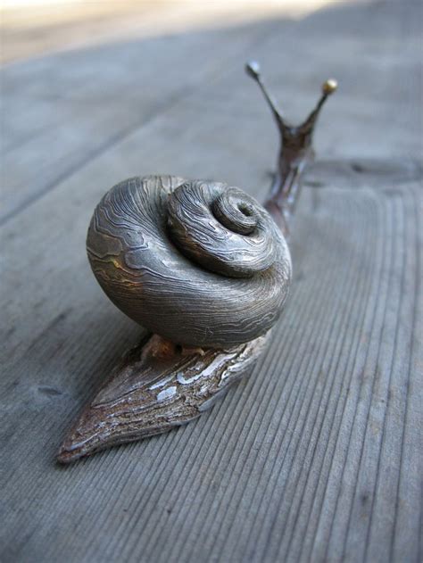 A Snail Is Sitting On Top Of A Piece Of Wood