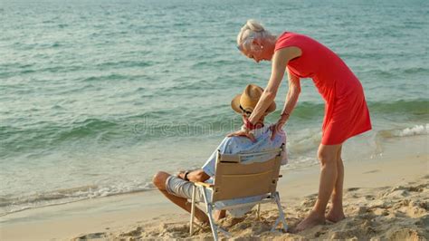 An Elderly Couple Hugs Their Shoulders At The Beach On Their Summer