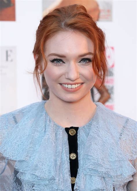 A Woman With Red Hair Wearing A Blue Blouse And Black Tie Smiling At