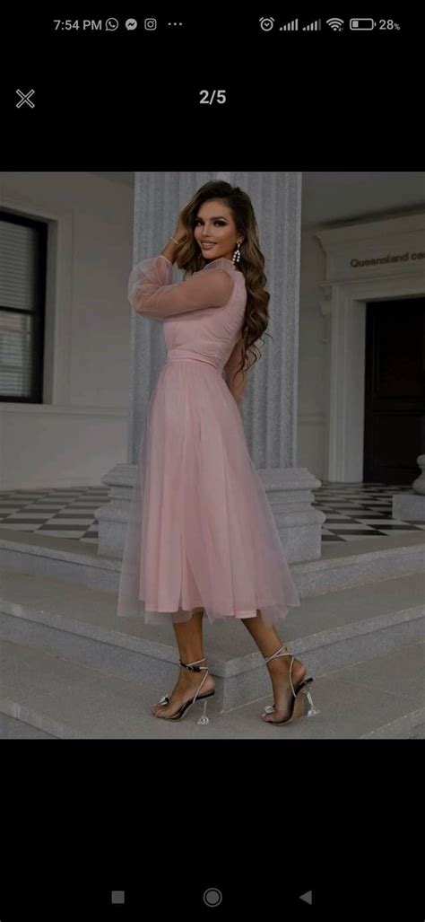 A Woman In A Pink Dress Is Standing On Steps With Her Arms Behind Her Head