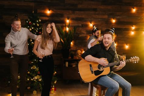 Los jóvenes felices bailan y cantan en la fiesta de navidad Foto Premium