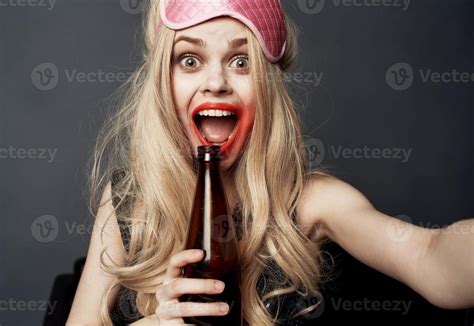 Drunk Woman With A Bottle Of Beer On A Gray Background Gestures With Her Hands And Bright Makeup