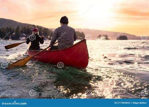 Couple Friends On A Wooden Canoe Are Paddling In Water Stock Photo