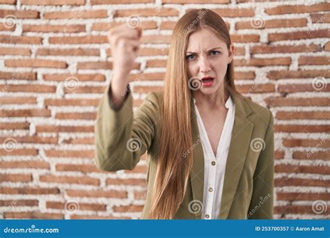 Young Caucasian Woman Standing Over Bricks Wall Background Angry And Mad Raising Fist Frustrated