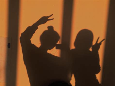 The Shadow Of Two People Holding Up Their Hands In Front Of A Wall With