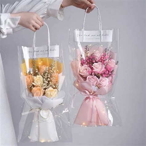 Two Clear Bags With Flowers In Them Being Held By Someone S Hand And