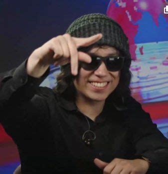 A Man Wearing Sunglasses And A Beanie Pointing To The Side With His