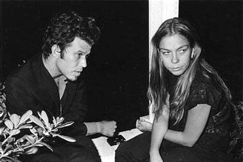 a man and woman sitting next to each other in front of a window looking ...