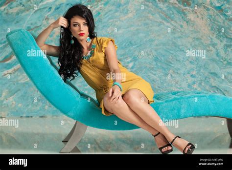 Elegant Brunette Woman Sitting On Blue Velvet Sofa Against Marble Tiles Wall Stock Photo Alamy
