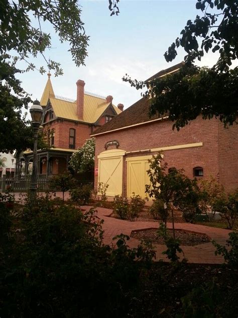 An Old Brick House With Yellow Shutters On The Front And Side Doors