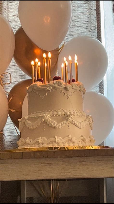 A Birthday Cake With White Frosting And Lit Candles On It Surrounded