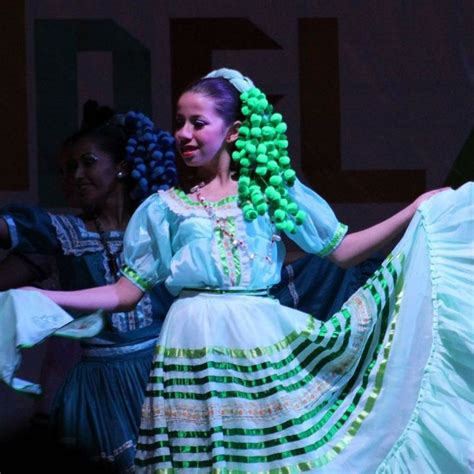 A Woman In A Green And White Dress Is Dancing With Other Women On Stage