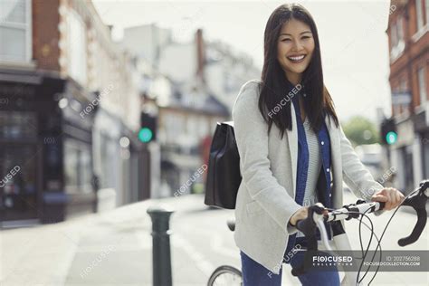 Portrait Smiling Businesswoman Commuting On Bicycle On Sunny Urban